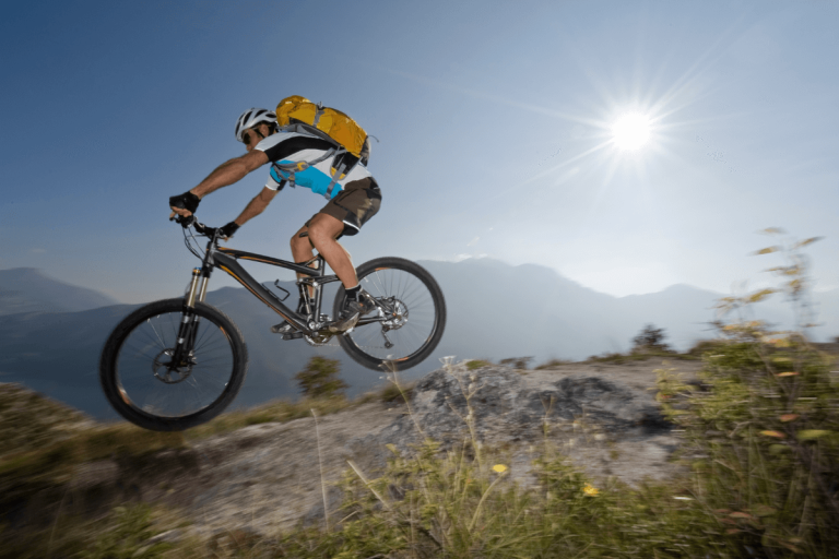 Moški s kolesom v gorah skoči s skale.