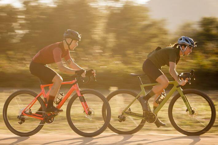 Kolesarja ob sončnem zahodu drvita po makedamski cesti.