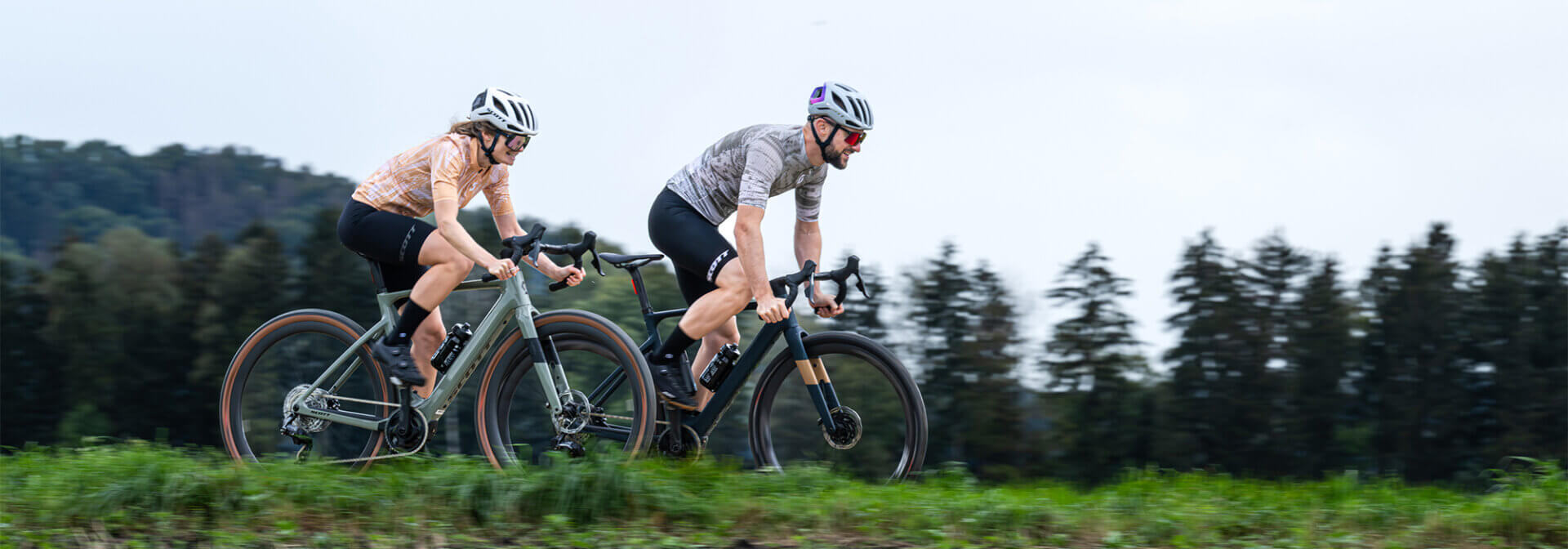 Par vozi po cesti med travniki električno cestno kolo.