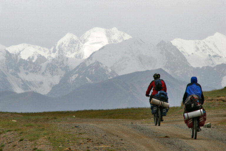 Turna kolesarja na makedamu z gorami v ozadju.